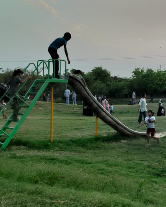 Children playing on a slide in a green urban park, documented during fieldwork
