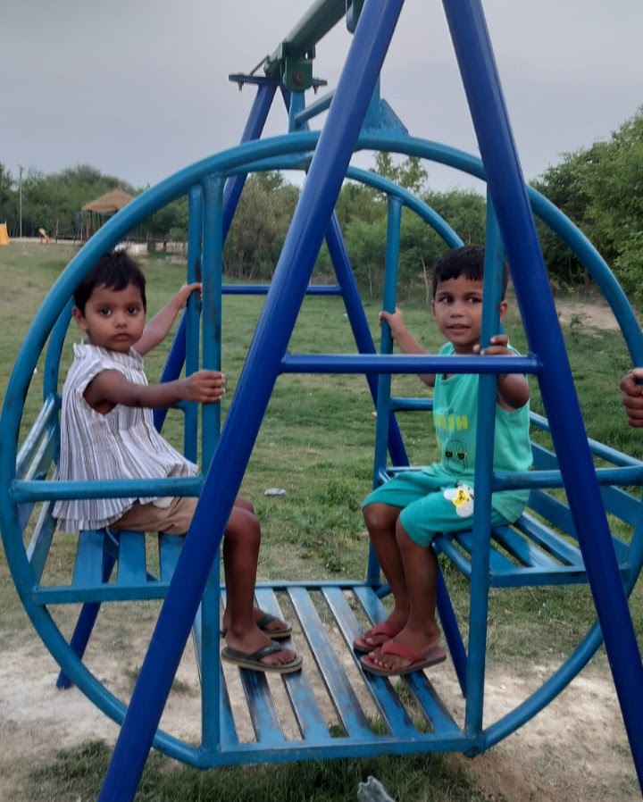 Two children on a swing in a green park, documented during fieldwork