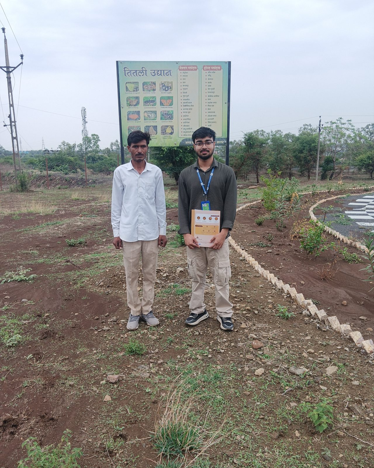 Arkraj Biswas with a field worker at a project site with an interpretive garden sign, documented during fieldwork